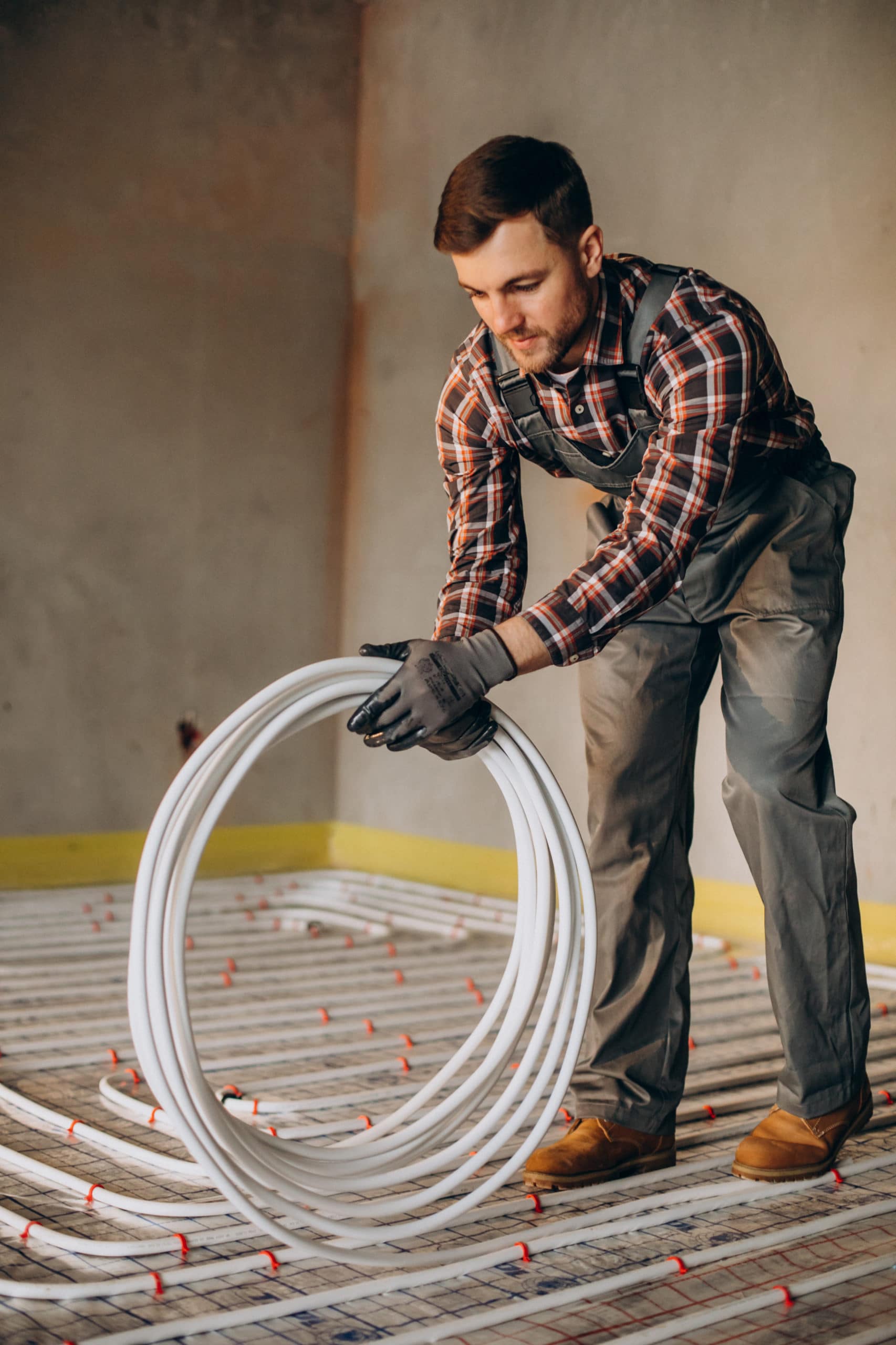 Service man instelling house heating system under the floor